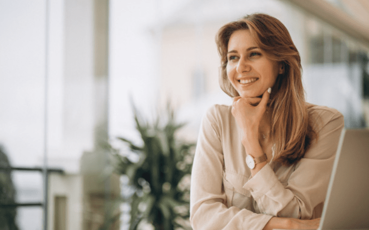 Small picture of a business woman thinking.  Her laptop is open next to her.