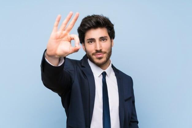 A familiar photo of a smart, satisfied businessman on a blue background.  He is indicating a gesture of approval.