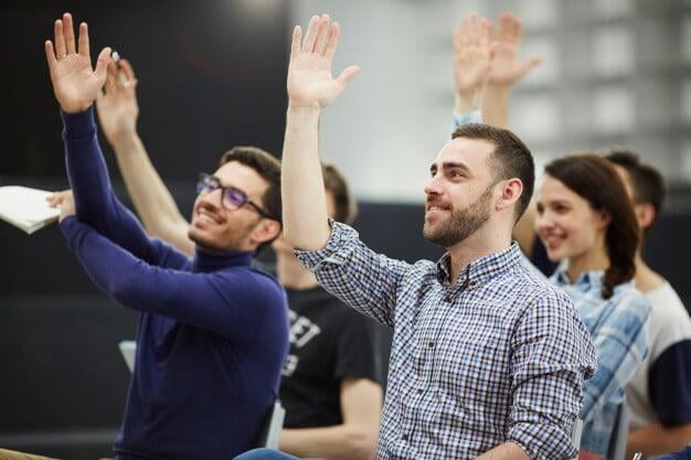 Several students in class raising their hands